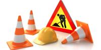 Image of hard hat, construction cones and men working sign