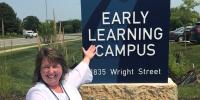 Staff member in front of the Early Learning Campus sign